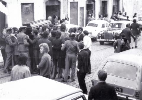 Funeral de José António Ribeiro Santos cercado pela polícia, 14 de outubro de 1972, ANTT (Junto à urna, são reconhecíveis, do lado esquerdo próximo dos polícias, João Soares e, mais atrás, José Galamba de costas, e António Abreu. Do lado direito, de camisa branca, António Monteiro Cardoso. Do lado direito da imagem, junto a um carro, Aurora Rodrigues)