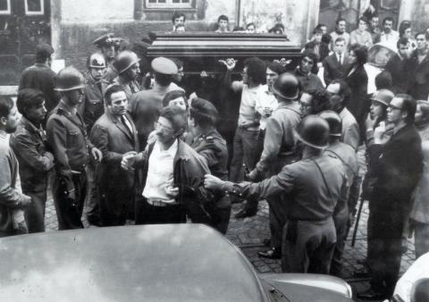Funeral de José António Ribeiro Santos cercado pela polícia, 14 de outubro de 1972 (ANTT). Entre um polícia de choque de capacete e a urna, distingue-se António Manuel Monteiro Cardoso e, ao fundo, junto à parede, Danilo Matos.